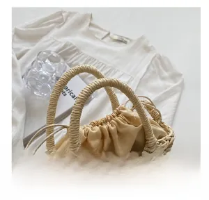 Detail of hand-woven straw bag showing natural fiber texture and green crochet leaf