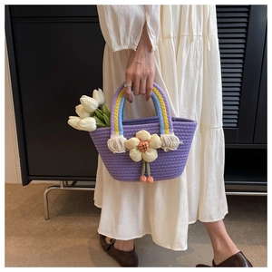 Detail of purple woven tote with 3D cream flower and rainbow handle on white dress