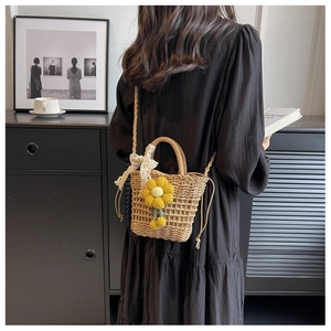 Detail of straw bucket bag with knitted sunflower and lace bow on a black dress model