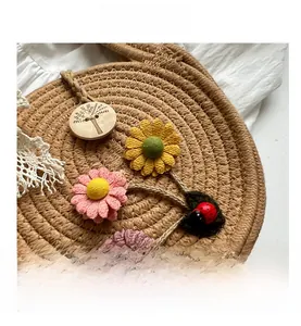 Detail der runden Strohtasche mit Häkelblumen, Marienkäfer-Anhänger und Holzknopf