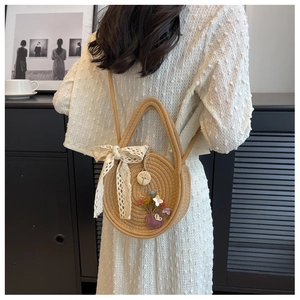 Détail d'un sac rond en paille avec broderie florale et nœud en dentelle blanche
