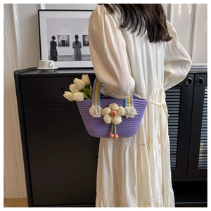 Detail of purple woven tote bag with large floral accents on a model in modern interior