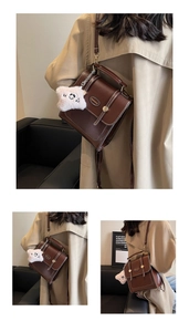 Close-up of vintage brown PU leather backpack featuring a cute panda plush keychain charm