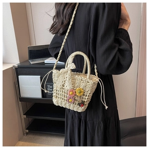 Detail of hand-woven straw bucket bag with floral accents and lace bow decoration