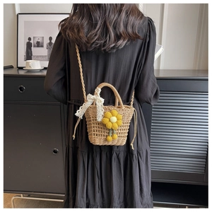 Detail of straw woven bag featuring a crochet sunflower charm and delicate lace bow