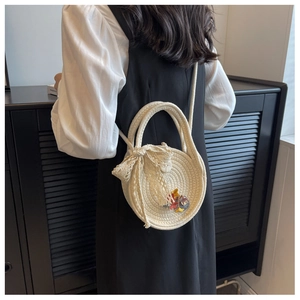 Vue détaillée du sac rond en paille blanche avec nœud en dentelle porté par un mannequin