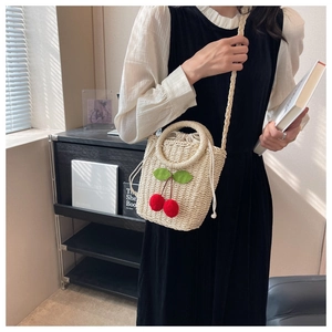 Detail of straw bucket bag with red cherry accents and drawstring inner pouch