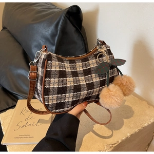 Detail of retro plaid wool armpit bag with cherry charm on beige stone pedestal