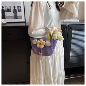 Detail of a purple woven handbag with yellow floral decor and rainbow striped handle