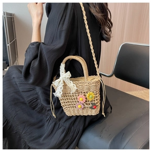 Detail of hand-woven straw tote with 3D floral accents and white lace bow decoration