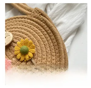 Detail der handgewebten runden Strohtasche mit 3D-Sonnenblumen und rosa Blumenakzenten