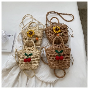 Detail of straw woven beach bags with floral patches and drawstring liners
