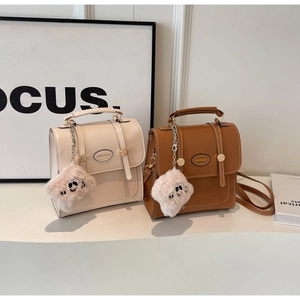Detail of vintage PU leather handbags with buckle straps and plush smile pendants