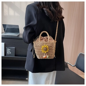 Detail of hand-woven straw beach bag with yellow sunflower charm and drawstring lining