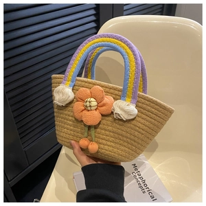 Detail of hand-woven straw tote bag with rainbow handles and orange flower decor