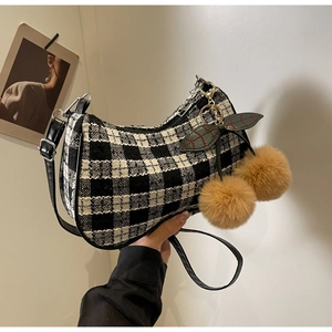 Detail of black and white checkered tweed handbag with fuzzy brown cherry charm pendants
