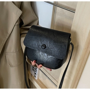 Close-up of retro black crossbody bag featuring textured PU leather and round buckle detail