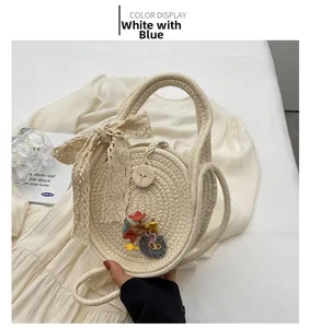 Détail du sac rond tressé beige avec nœud en dentelle et appliques florales colorées