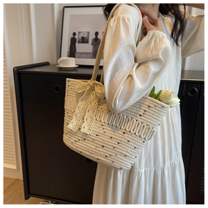 Détail du sac de plage tissé en paille avec nœud en dentelle et décoration de tulipe