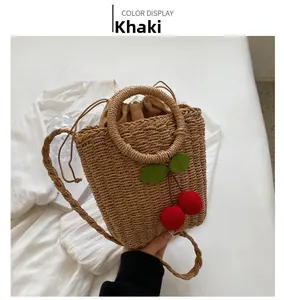 Detail of khaki straw shoulder bag featuring textured 3D plush cherry decorations