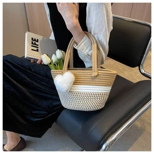 Detail einer handgewebten gestreiften Beuteltasche mit Herzanhänger und weißen Tulpen