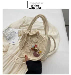 Détail d'un sac à main rond en paille avec nœud en dentelle, fleurs et bouton en bois