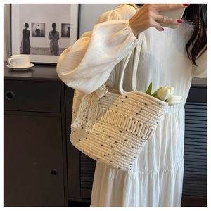 Détail du sac de plage tissé avec nœud en dentelle et taches bleues en selfie miroir