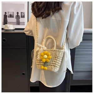 Detail of hand-woven straw bag featuring yellow crochet flower and white lace bow
