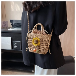 Detail of hand-woven straw beach bag featuring yellow sunflower appliques and drawstring liner