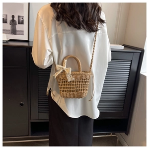 Detail of hand-woven straw crossbody bag with lace bow decoration and hollow mesh pattern