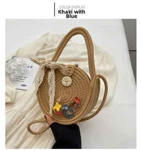 Détail du sac rond en paille kaki et bleu avec nœud en dentelle et fleurs