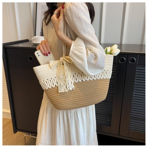 Détail du sac de plage tressé avec grand nœud en dentelle et motif en paille bicolore