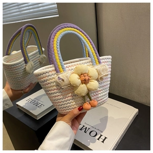 Detail of woven straw bag featuring a rainbow handle and a large yellow 3D flower