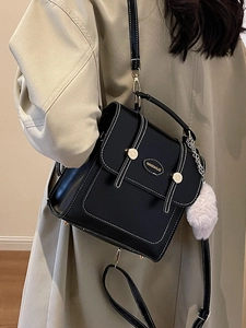 Vintage black leather backpack for women with white stitching and plush charm