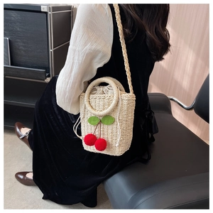 Detail of straw bucket bag with red cherry accents and a drawstring lining for women