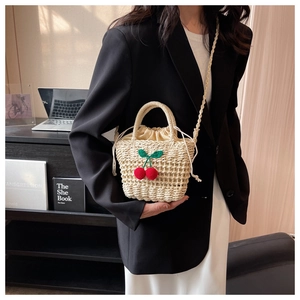 Detail of handmade straw bag with woven red cherries and practical drawstring liner