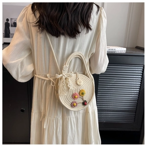 Detailansicht einer runden Strohtasche mit Gänseblümchen-Dekor und Spitzen-Schleife