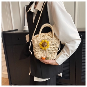 Detail of hand-woven straw bag featuring sunflower decor and adjustable crossbody strap