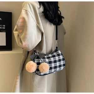 Detail of checkered underarm bag with cute plush cherry pompom pendant on shoulder strap