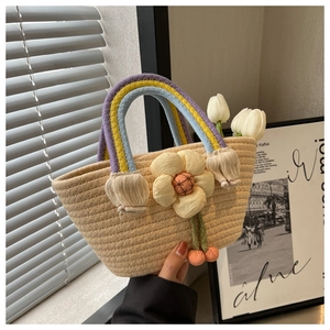 Detail of woven straw handbag featuring a colorful rainbow handle and floral charms