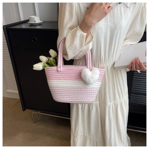 Nahaufnahme der rosa-weiß gewebten Tasche mit weißem Plüsch-Herzanhänger und Blumendetail