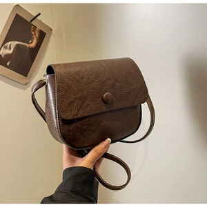 Detail of vintage brown shoulder bag with frosted texture and circular buckle clasp
