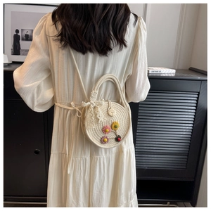 Detail der handgewebten Strohtasche mit Blumenakzenten und Spitzenschleife für den Urlaub