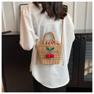 Close-up of handmade woven straw bag with green leaves and 3D red cherry decorations