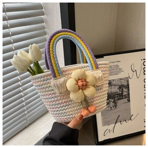 Detail of woven straw bag with colorful handles and decorative floral tassel ornament