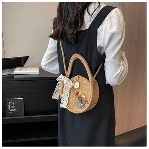 Détail du sac bandoulière rond en paille avec nœud en dentelle et appliques colorées