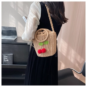 Detail of woven straw bucket bag with red cherry accents and a drawstring lining