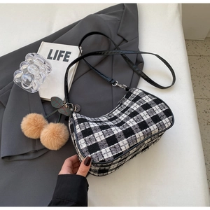 Detail of black and white tweed crescent bag with elegant furry pompom charm