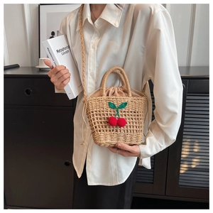 Detail of hand-woven straw beach bag with cherry crochet decor and drawstring liner