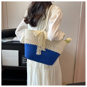 Détail du sac cabas tissé avec panneaux contrastés bleu et blanc et nœud en dentelle délicat